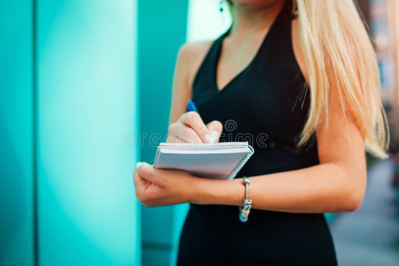 Young blonde businesswoman writing notes in notepad. Asssistant putting down tasks in notebook royalty free stock photo Young blonde businesswoman writing notes in notepad. Asssistant putting down tasks in notebook royalty free stock photo