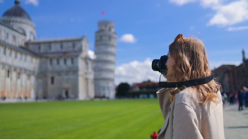 Young 30s female tourist taking photos of the famous Leaning Tower of Pisa. Vacation in Italy, traveling off season.