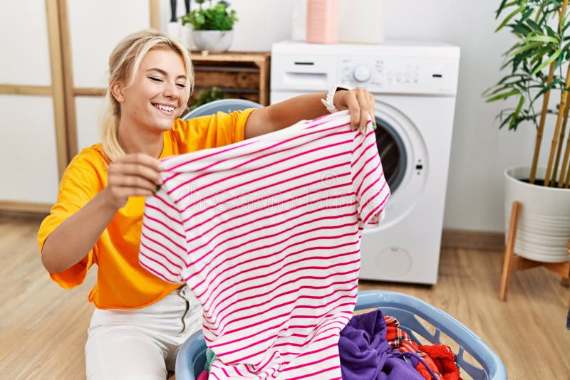 Young Blonde Girl Doing Laundry Putting Clothes into Washing Machine at ...