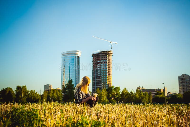 Young blonde girl in dress with shoulder bag, walking on dandelion field royalty free stock image Young blonde girl in dress with shoulder bag, walking on dandelion field royalty free stock image