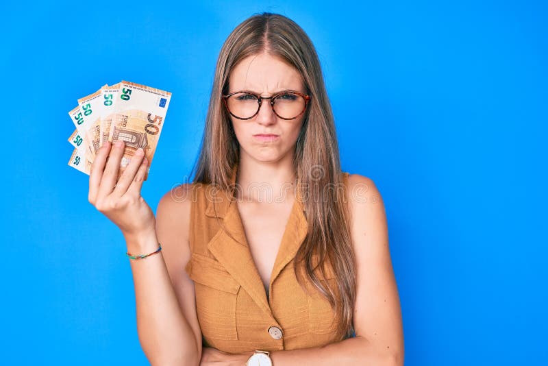 Young blonde girl holding euro banknotes skeptic and nervous, frowning upset because of problem