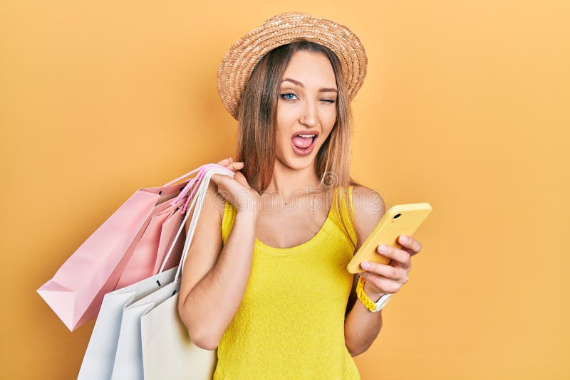 Young Blonde Girl Holding Shopping Bags Using Smartphone Winking ...