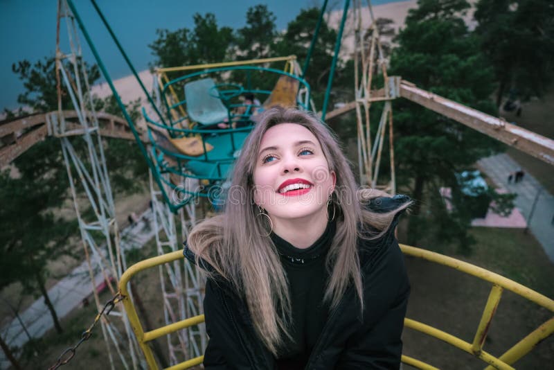 Young Blonde Girl Rides On Rusty Ferris Wheel At Spring Stock Image