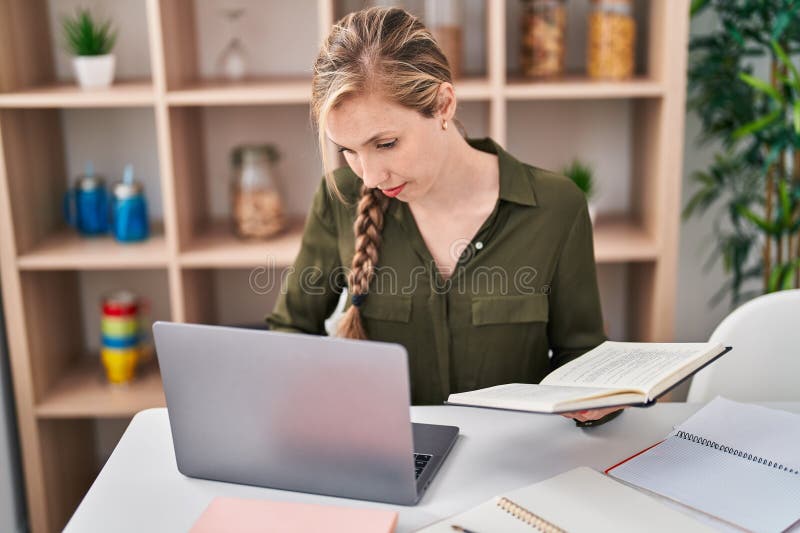 Young blonde woman sitting on table studying at home stock photography