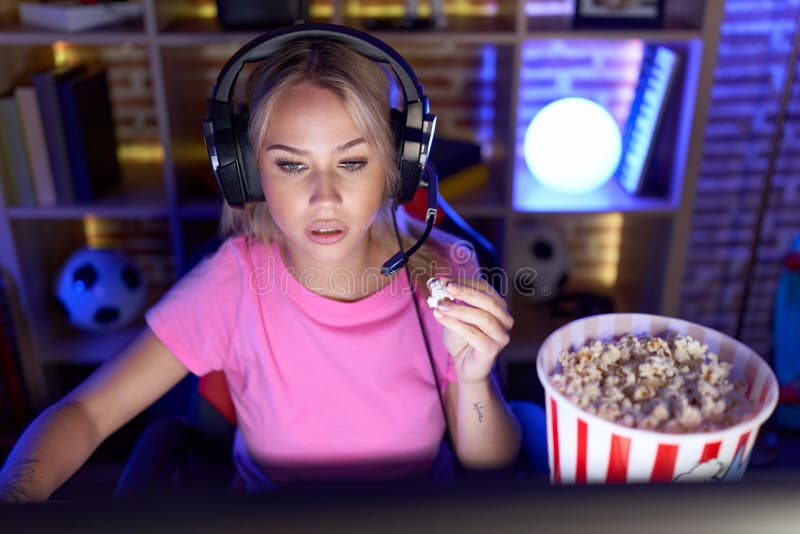 Young Blonde Woman Streamer Playing Video Game Eating Popcorn At Gaming