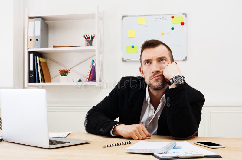 Young bored businessman with laptop in modern white office royalty free stock photo Young bored businessman with laptop in modern white office royalty free stock photo