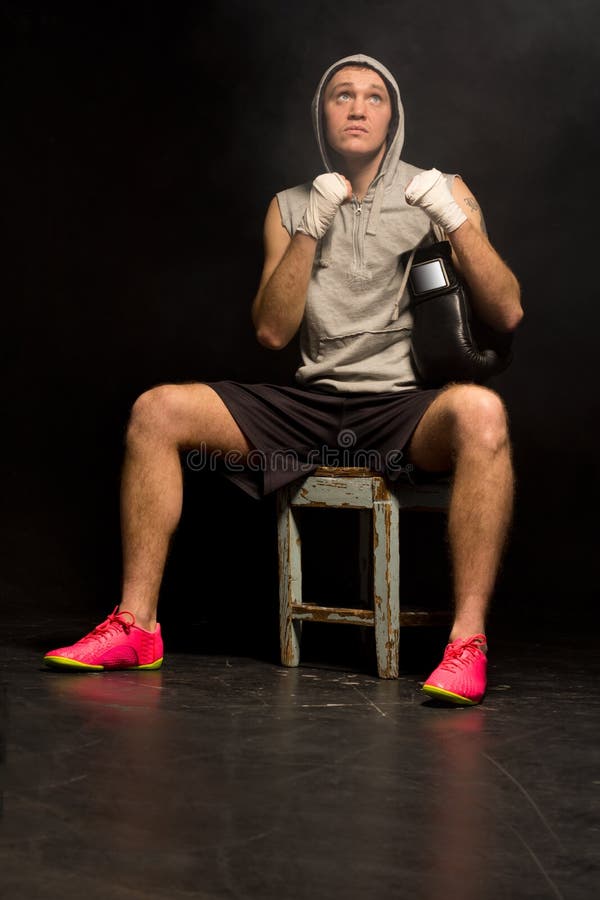 Young boxer sitting looking up to heaven as he prays for a win before heading into the ring for a fight