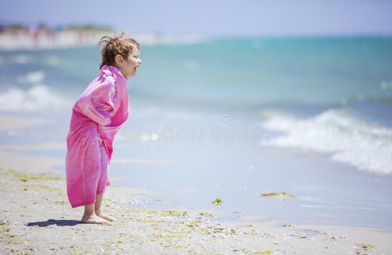 Young boy in beach towel laughing while playing near water stock images Young boy in beach towel laughing while playing near water stock images