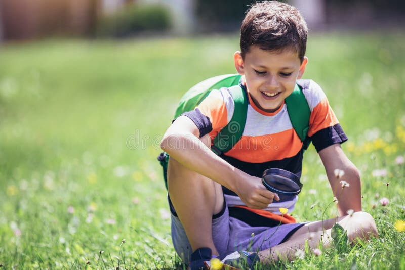 Boy exploring nature in a meadow with a magnifying glass royalty free stock photo