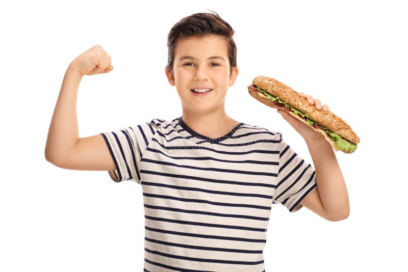 Young boy flexing his biceps and holding a sandwich isolated on white background