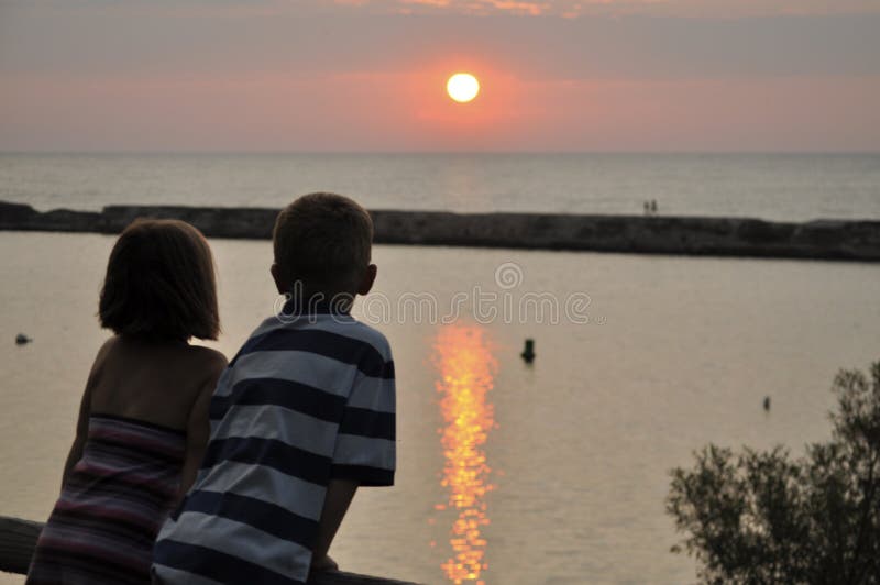 Young boy and girl overlooking sunset and water