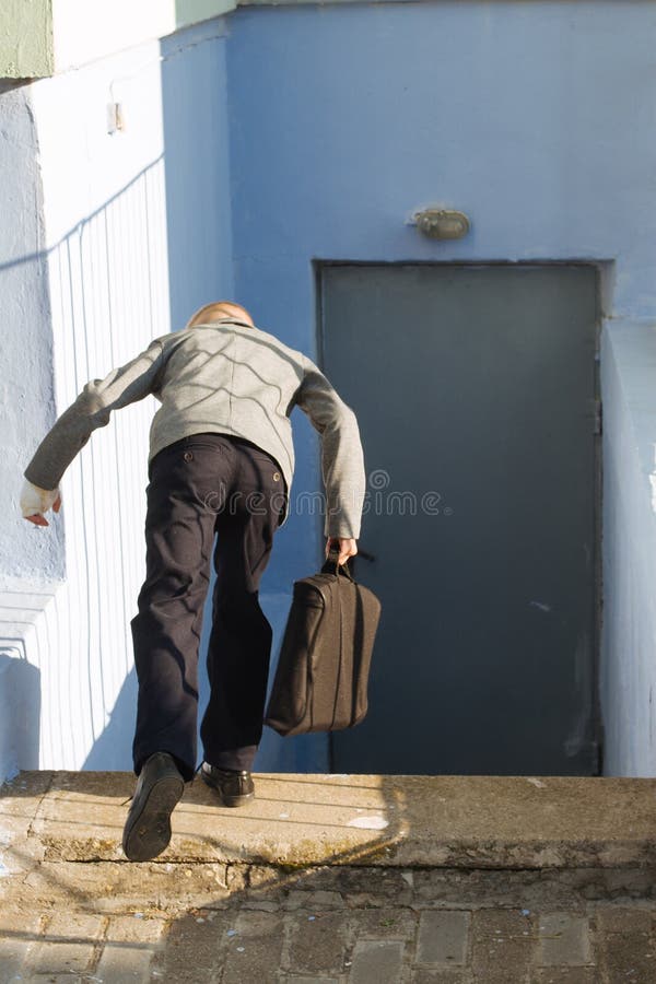 Young boy in a gray jacket with a briefcase falls from stairs edge down stock image Young boy in a gray jacket with a briefcase falls from stairs edge down stock image