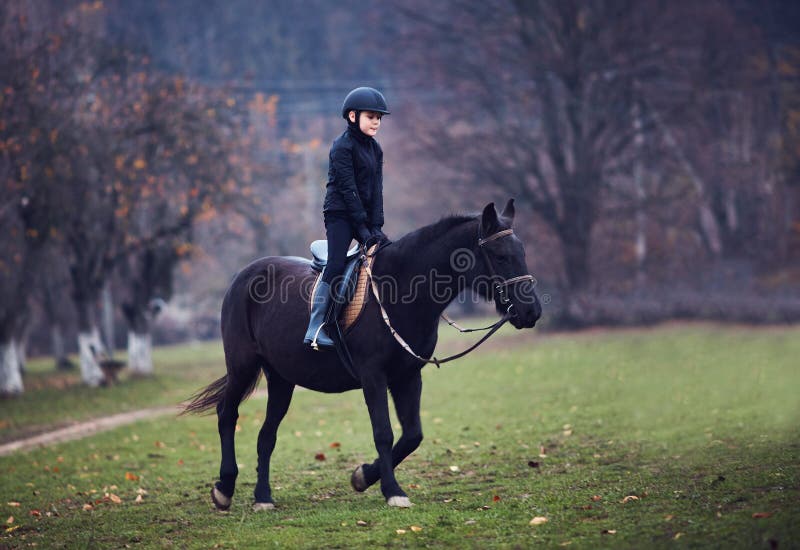 Young boy, kid is taking a horse riding lesson, equestrian sport, horseback rider outfit