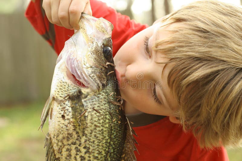 Young boy kissing fish he caught