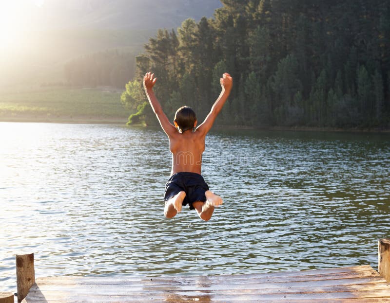 Young boy leaping into lake