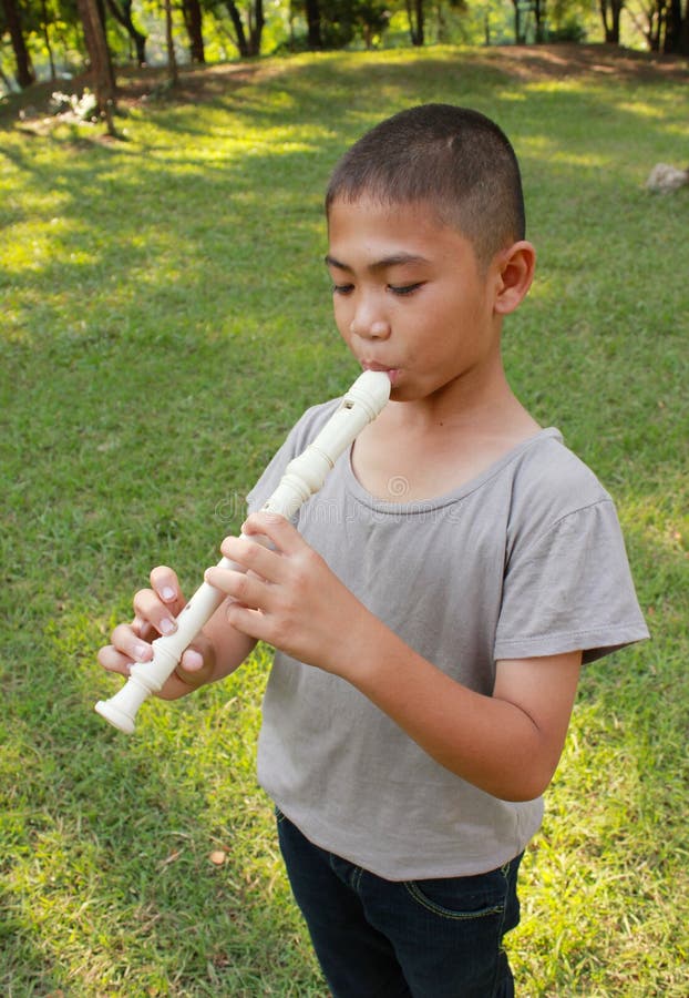 Young boy playing flute in park stock photos