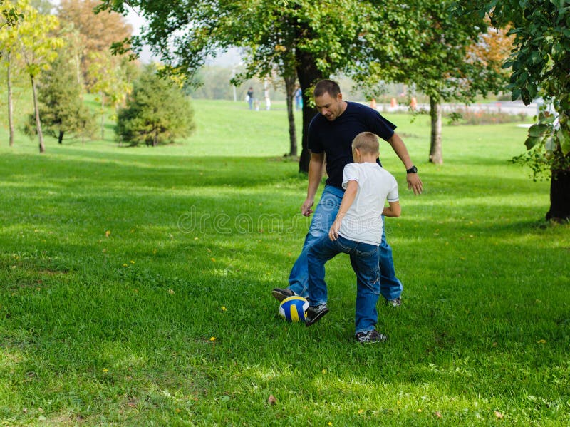 Young boy playing football with his father
