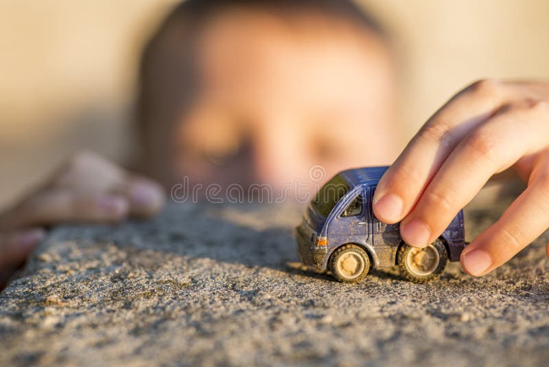 Young boy plays with toy car. Little boy playing with car toy on sunset