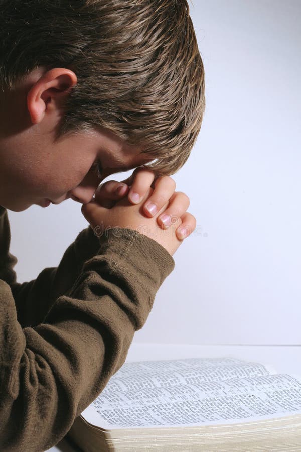 Young boy praying over his bible stock photo Young boy praying over his bible stock photo