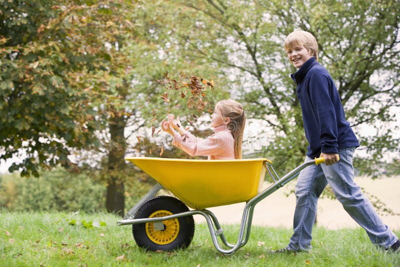 Young boy pushing girl in wheelbarrow