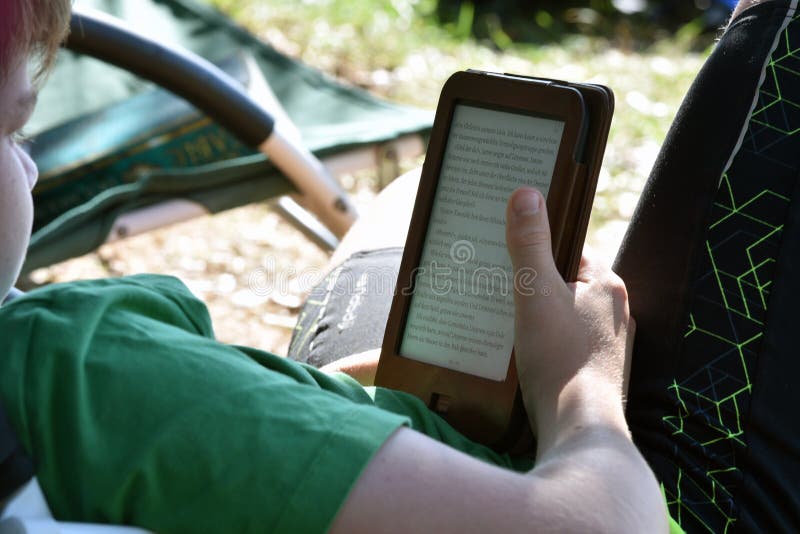 Bale / Croatia -7/18/2019: Young boy reading a book on Kindle device or tablette.