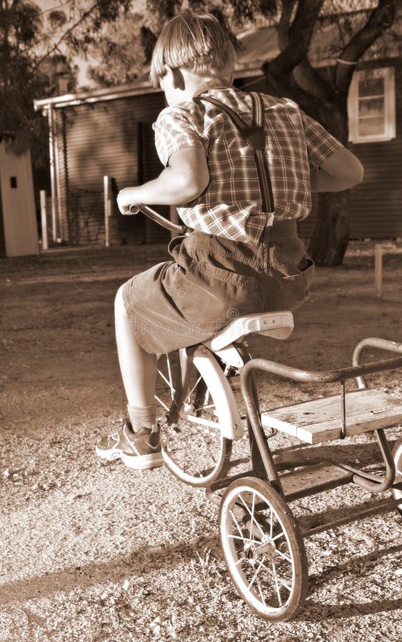 Young boy in old style clothing rides a tricycle. Young boy in old style clothing rides a tricycle