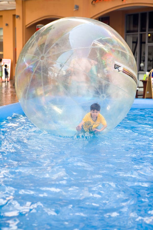 Young boy in rubber ball floating on water