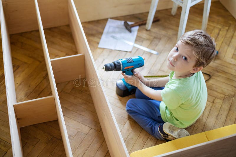 Young boy with screwdriver looking up while sitting on floor