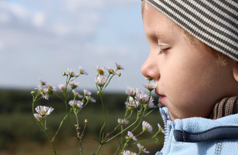 Young boy smelling flower