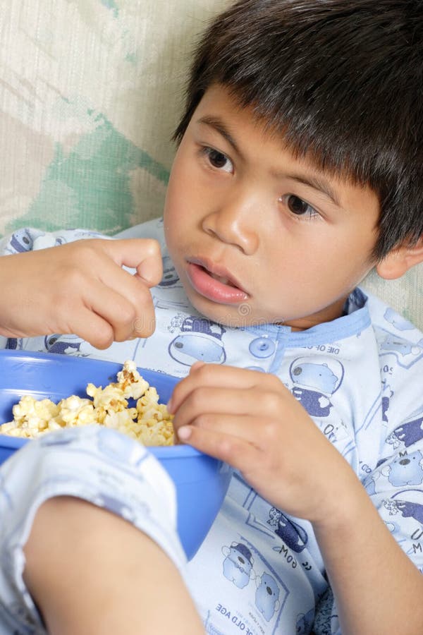 Mladý chlapec, svačiny, na popcorn při sledování filmu doma.