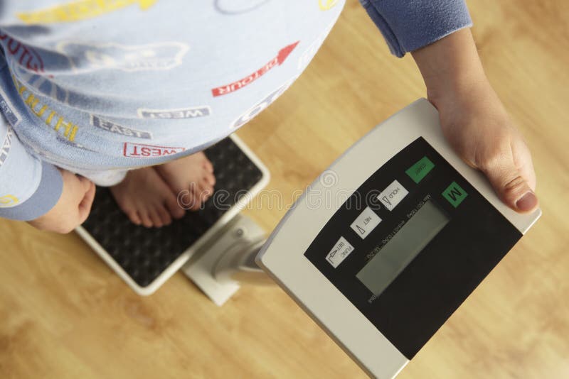 Young boy standing on digital scales cropped waist down