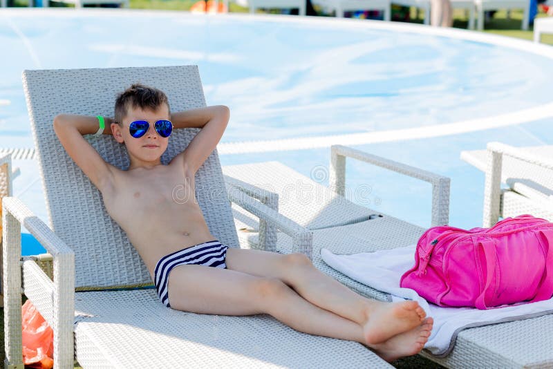 Young boy in a swimsuit on a shelf by the pool