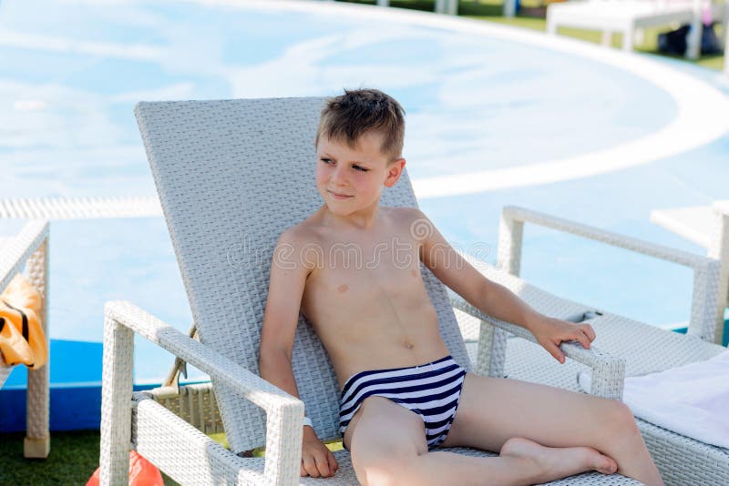 Young boy in a swimsuit on a shelf by the pool