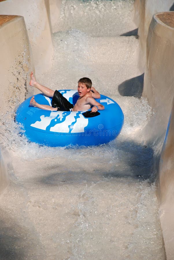 Immagine di un giovane ragazzo di divertirsi in sella a una metropolitana in una località di villeggiatura con piscina.