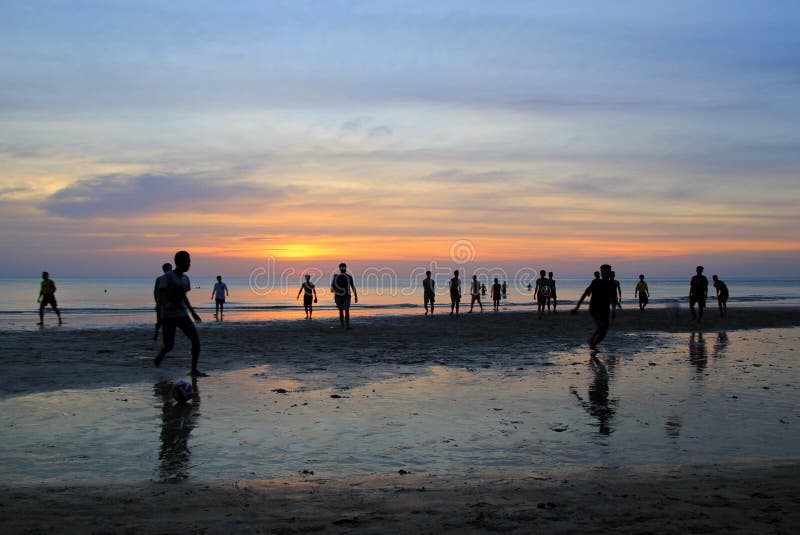 The young boys are playing football on the beach on the background of colorful sunset. royalty free stock photography The young boys are playing football on the beach on the background of colorful sunset. royalty free stock photography