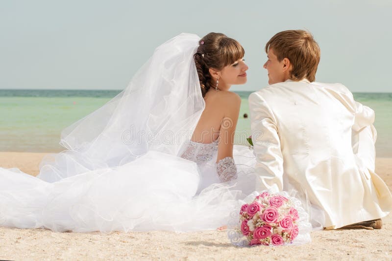 Young bride and groom on the beach stock image