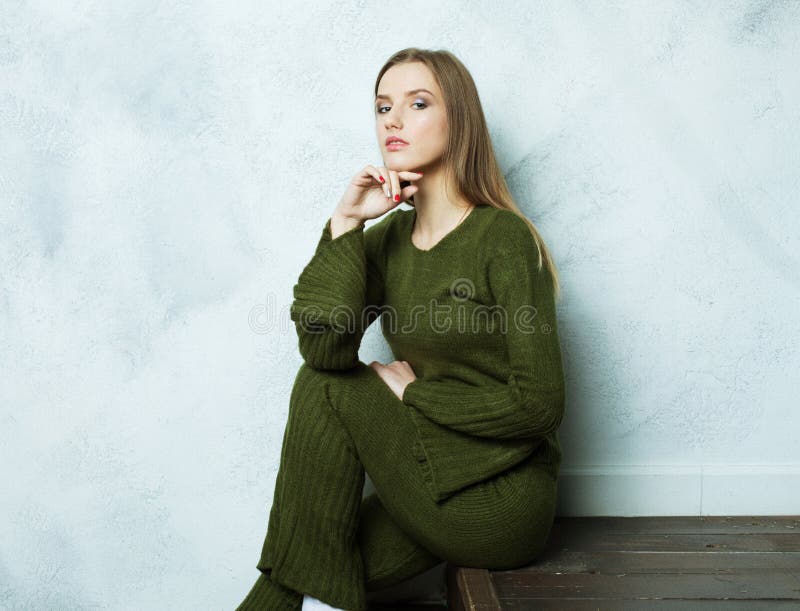 Young brown-haired woman with long hairs dressed in a green knitted suit, relaxation and rest.