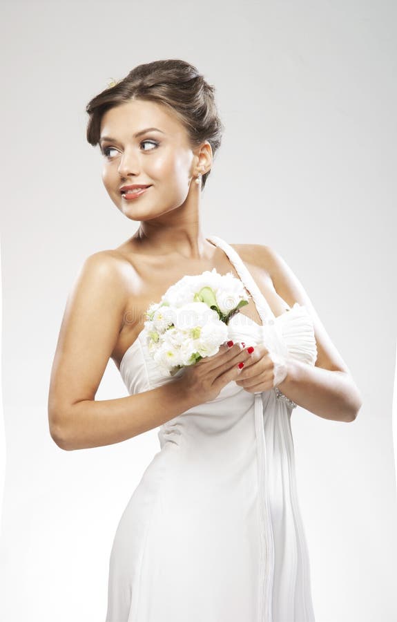 A young brunette bride holding a flower bouquet