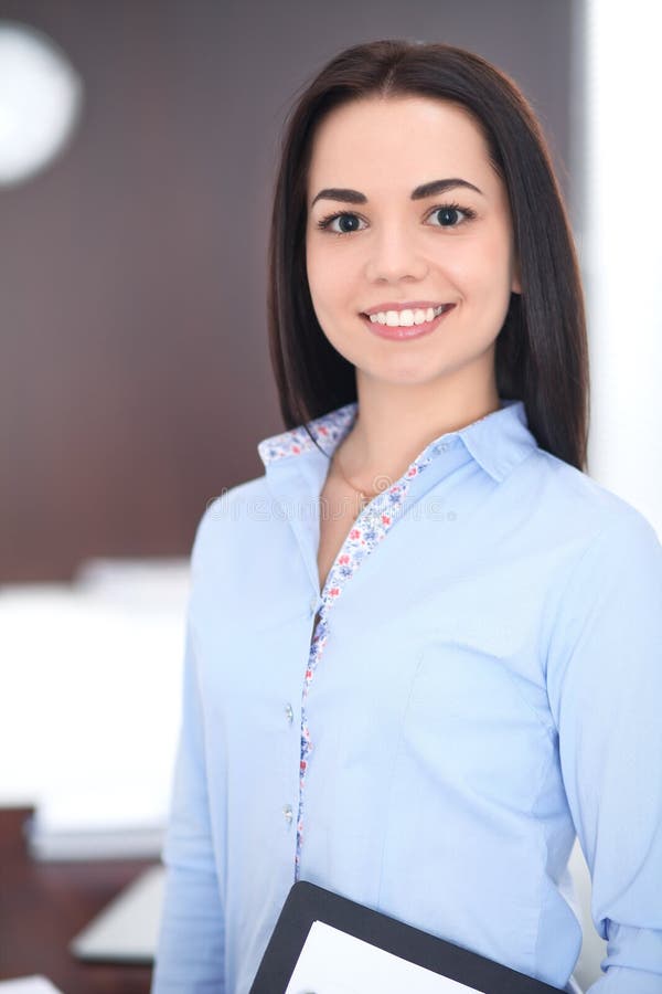 Young brunette business woman looks like a student girl working in office. Hispanic or latin american girl happy at work stock image Young brunette business woman looks like a student girl working in office. Hispanic or latin american girl happy at work stock image