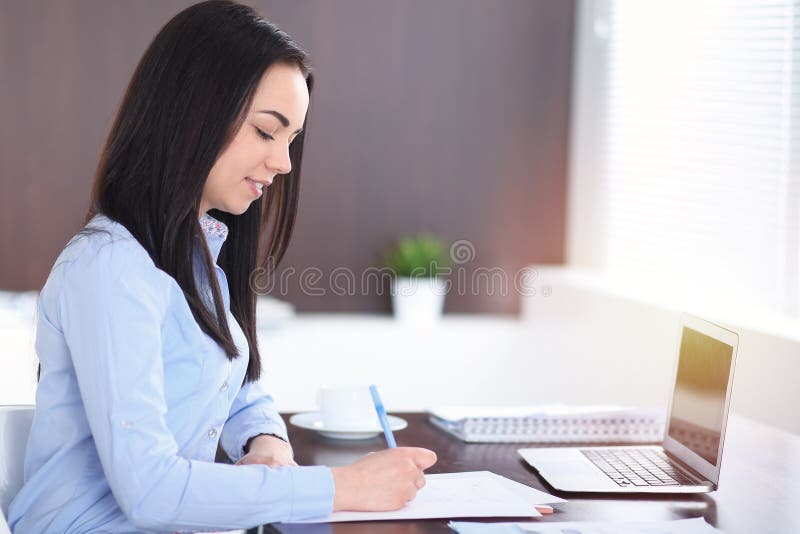Young brunette business woman looks like a student girl working in office. Hispanic or latin american girl happy at work stock photography Young brunette business woman looks like a student girl working in office. Hispanic or latin american girl happy at work stock photography