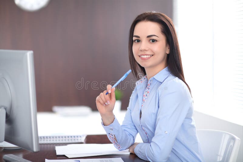 Young brunette business woman looks like a student girl working in office. Hispanic or latin american girl happy at work