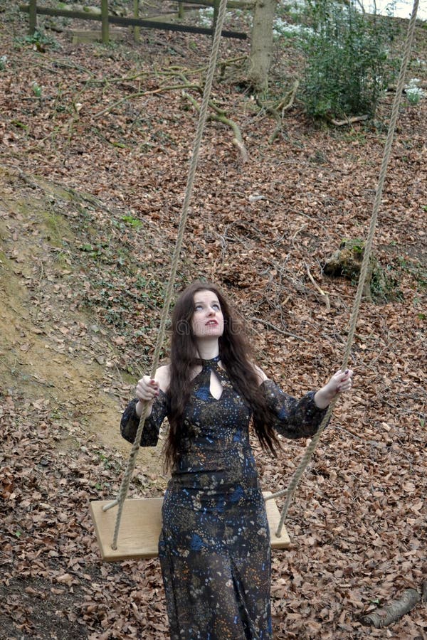 Young brunette caucasian lady testing the ropes of a swing in winter forest royalty free stock photo Young brunette caucasian lady testing the ropes of a swing in winter forest royalty free stock photo