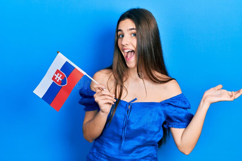 Mladá brunetka tínedžerka drží slovenskú vlajku oslavuje úspech so šťastným úsmevom a víťazným výrazom so zdvihnutou rukou