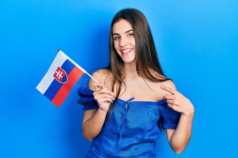 Mladá brunetka teenager drží slovenskú vlajku s úsmevom šťastný ukazuje rukou a prstom