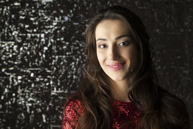 Young brunette woman on dark studio wall background. Cute, caucasian.