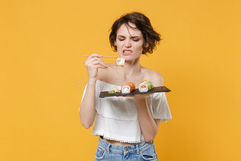 Young brunette woman girl in casual clothes hold in hand makizushi sushi roll served on black plate traditional japanese royalty free stock photos