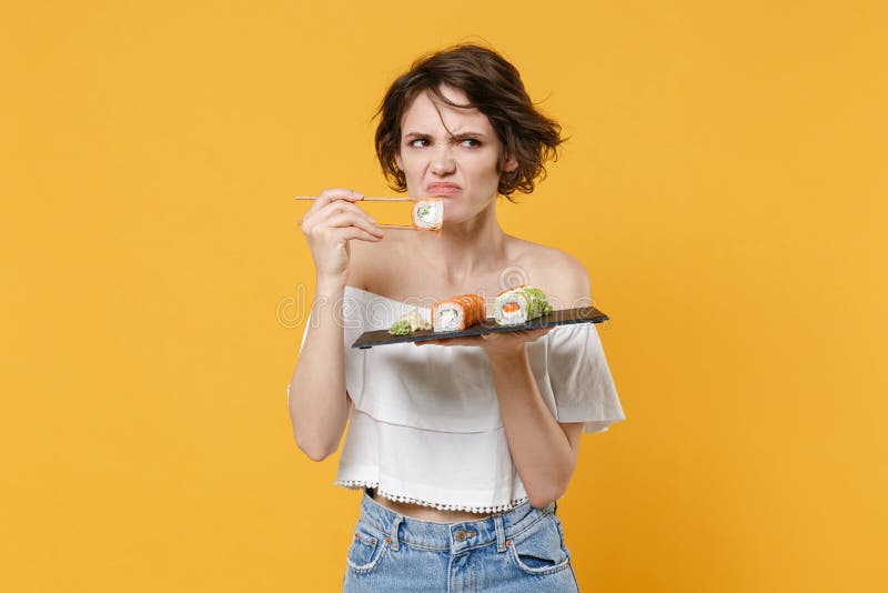 Young brunette woman girl in casual clothes hold in hand makizushi sushi roll served on black plate traditional japanese royalty free stock image