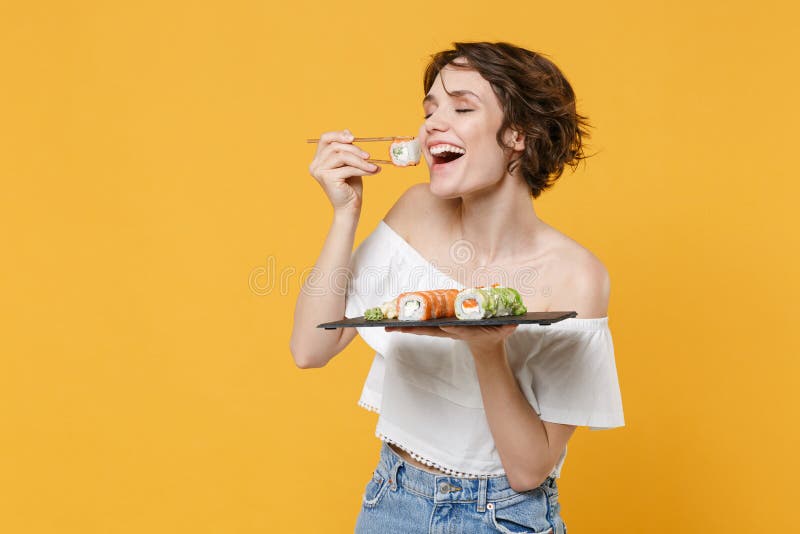 Young brunette woman girl in casual clothes hold in hand makizushi sushi roll served on black plate traditional japanese royalty free stock photography