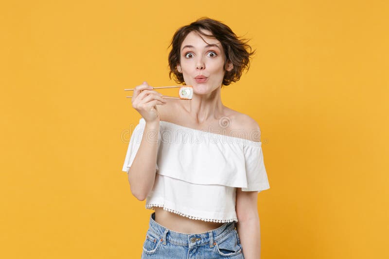 Young brunette woman girl in casual clothes hold in hand sticks chopsticks with makizushi sushi roll traditional stock photos