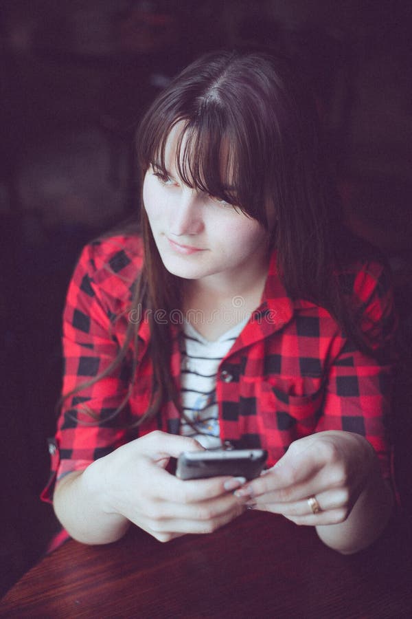 Young Brunette Woman In Red Checkered Shirt Sitting Near Window With